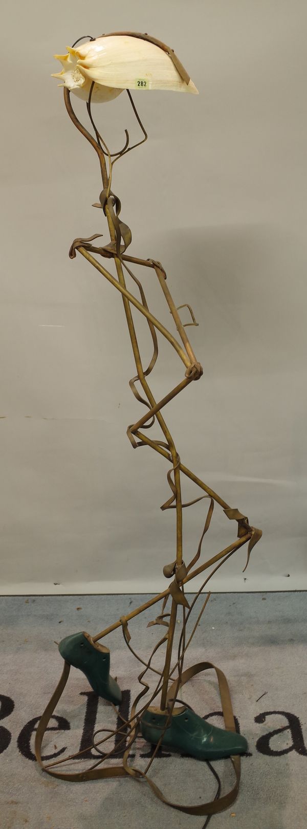 A 20th century abstract copper standard lamp in the form of a standing man with shell shade, 165cm high.   Provenance; property from the late Sir Davi