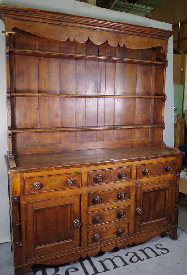 A late Victorian oak dresser with two long drawers and four short drawers, flanked by cupboard doors and a three tier plate rack, 166cm wide x 196cm h