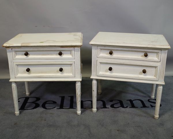 A pair of Louis XVI style white painted two drawer bedside chests on fluted tapering supports, 56cm wide x 60cm high.