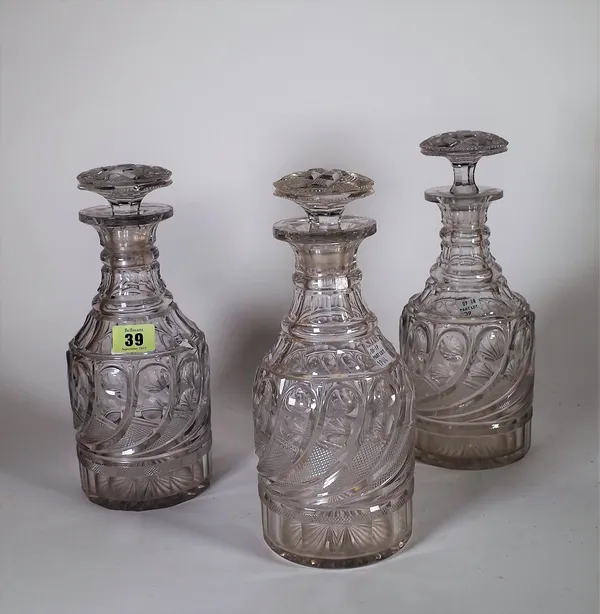 A set of three Regency cut glass decanters and stoppers, early 19th century, each cylindrical body cut with a band of gadroon shaped panels beneath a