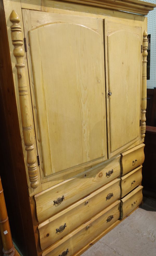 An early 20th century pine double wardrobe with arch panelled doors over three short and three long drawers on plinth base, 139cm x 189cm high.