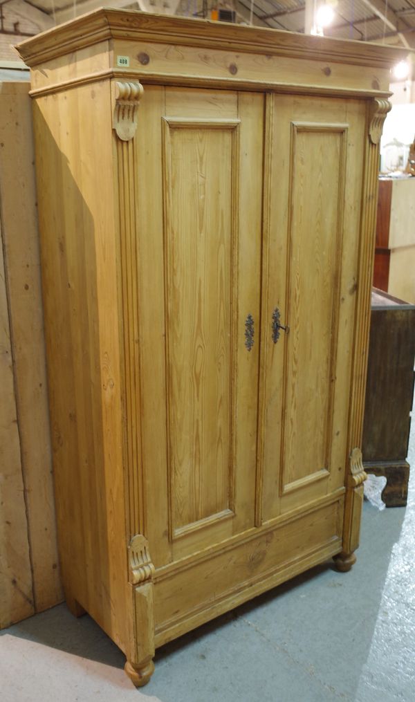 A Victorian style pine double wardrobe with panelled doors flanked by fluted edges on turned supports, 112cm wide x 185cm high.