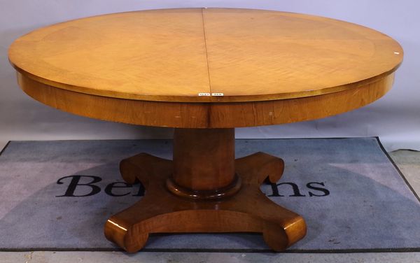 An Empire style walnut extending dining table, on turned column and four downswept supports, one extra leaf, 150cm diameter x 205cm long extended.