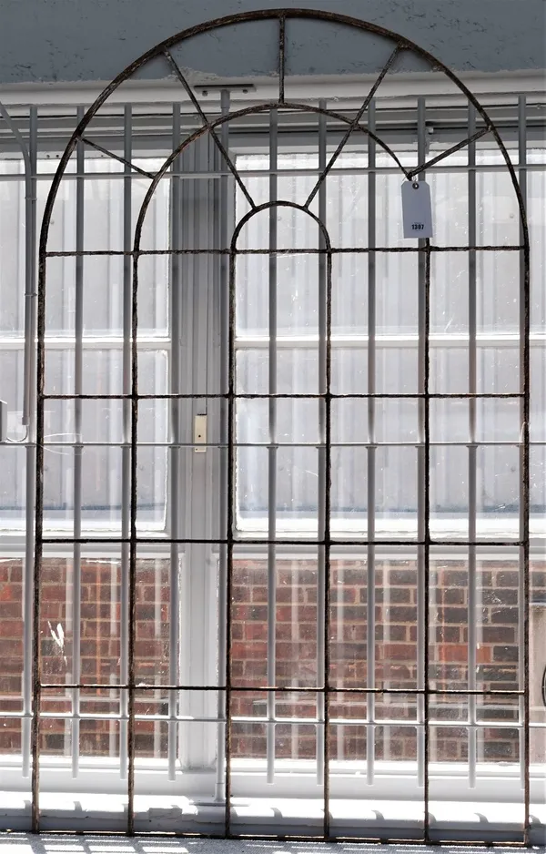 Wrought iron window frames, early 20th century, the first of arched, segmented form, 171cm high, the second of circular segmented form, 100cm diameter