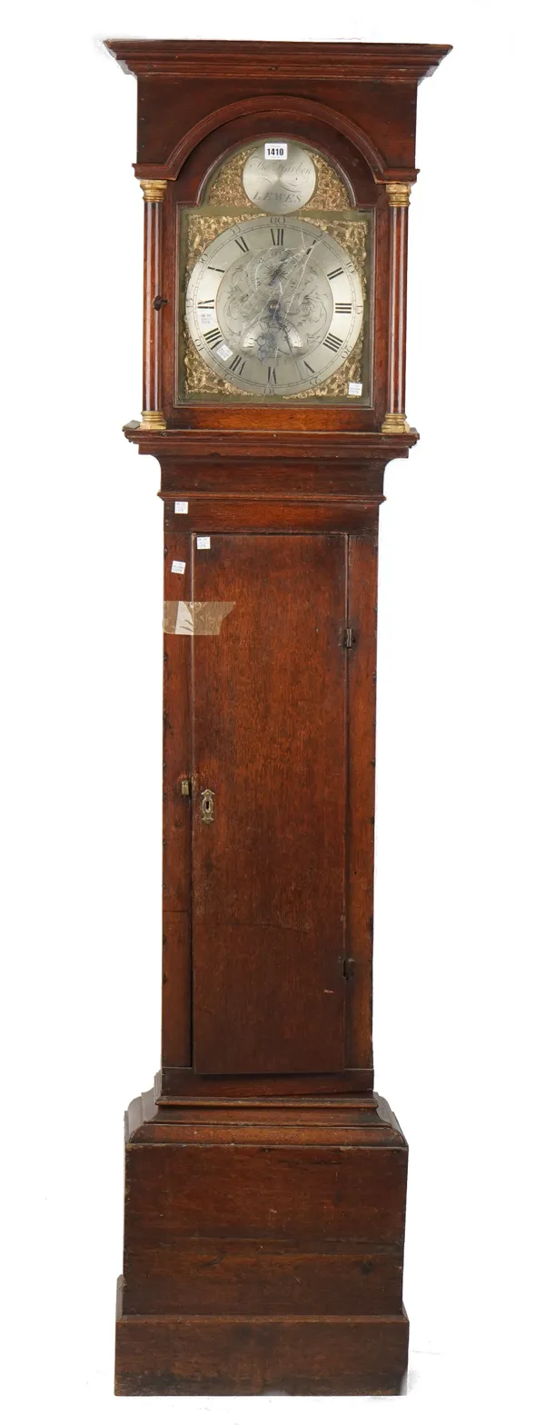 An 18th century oak longcase clock by Thomas Harben Lewes, with arch top hood, brass and silvered dial plate and weight driven movement over a waisted