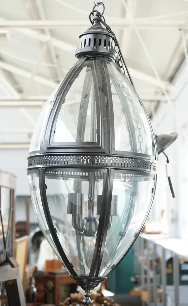 A modern patinated metal lantern of ovoid form, with glazed panels, pierced central circlet and internal four light fitment, 90cm high.