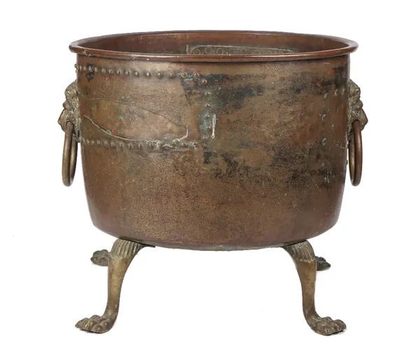 A 19th century copper log bin, of circular riveted form, with twin brass lion mask handles, raised on four lion paw supports, 57cm high x 58cm diamete