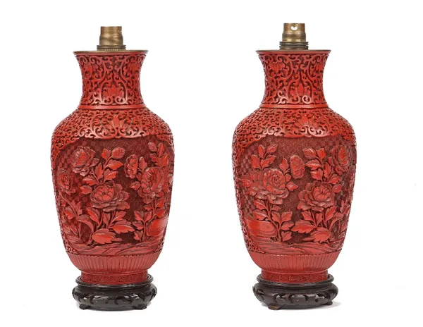 A pair of Chinese cinnabar lacquer vases (converted to table lamps), decorated with flowers against a further foliate carved ground, on wooden bases,