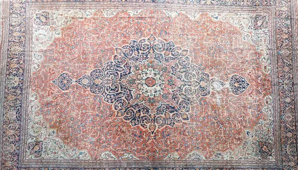 A large antique Kashan carpet, Persian, the madder field with a bold dark indigo, madder and sage medallion, ivory spandrels, all with delicate floral