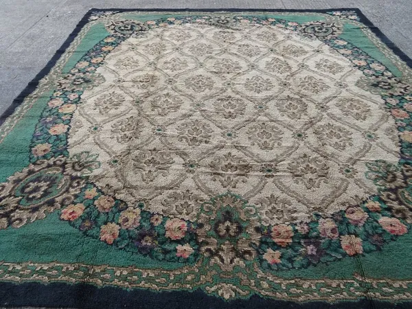 A Donegal carpet, the fan roundel with a trellis, each section centred with a flowerhead, a floral surround, a green outer surround, black border, 410