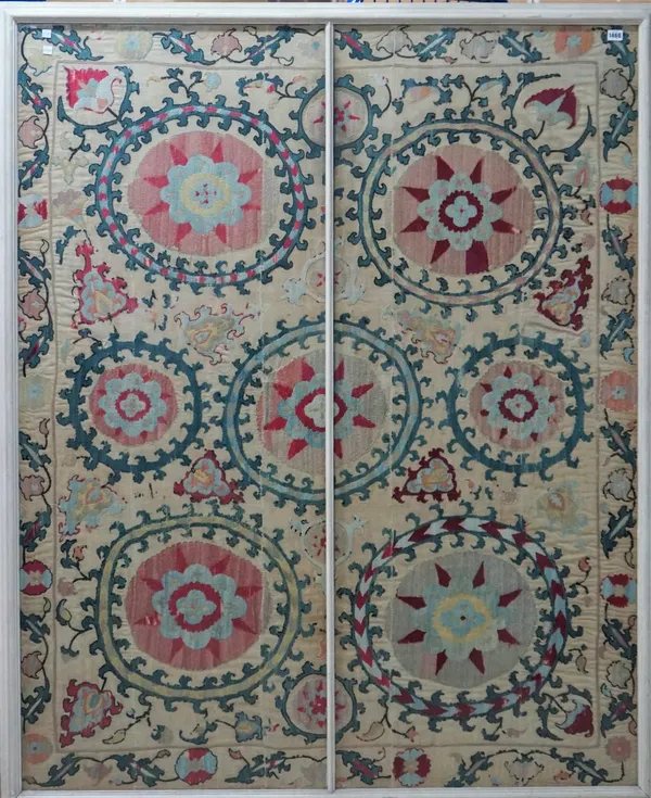 A Susani embroidered panel, the plain cotton field with seven large hooked roundels bearing flowerheads, a waved leaf and vine border, 159cm x 129cm.