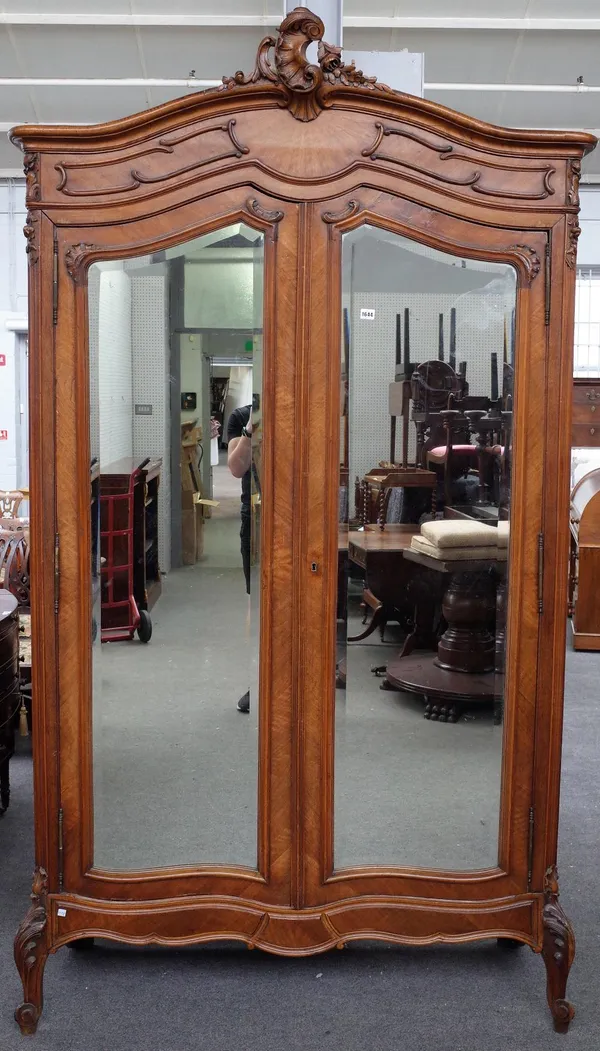 A 19th century French walnut armoire, with 'C' scroll crest over a pair of mirrored doors, on scroll feet, 135cm wide x 242cm high.