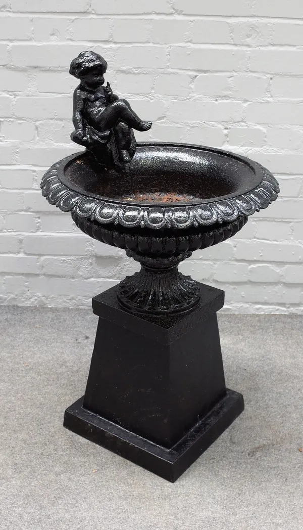 A black painted cast iron urn, cast with a seated cherub on square base, 55cm diameter x 98cm high.