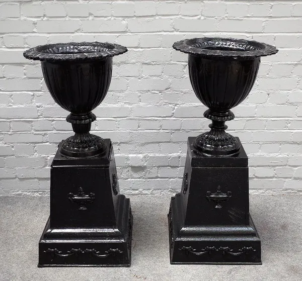 A near pair of black painted cast iron garden urns, on urn and swag moulded square bases, 45cm diameter x 108cm high.