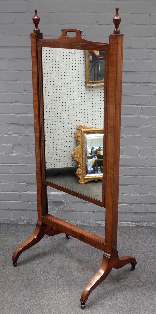 An early 19th century mahogany boxwood and ebony strung cheval mirror, the rectangular rising plate with cut-out handle, on downswept legs and castors