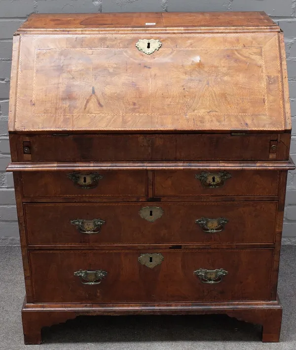 An early 18th century walnut cross and feather banded bureau, with a moulded caddy top, the fitted stepped interior having a well with sliding cover,