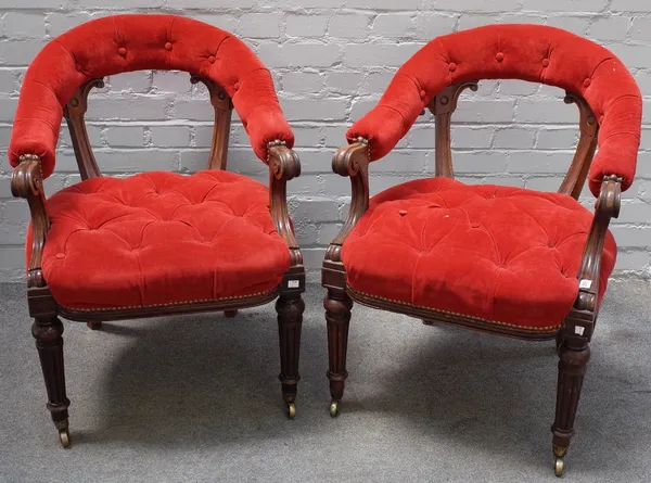 A pair of Victorian walnut frame library armchairs, circa 1870, with button down upholstered curved open backs and stuff-over seats, on turned and ree