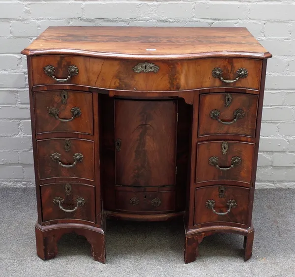 A George III mahogany dressing table, of serpentine outline, the frieze drawer above six pedestal drawers, the recessed kneehole cupboard with a drawe