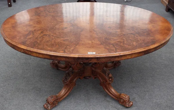 A Victorian figured walnut oval snap top loo table, on four carved downswept supports, 157cm long x 116cm wide. AFTERSALE