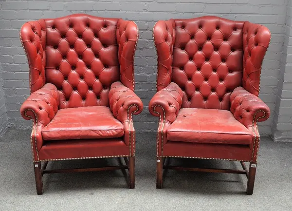 A pair of George II style red leather upholstered wingback armchairs on block supports, 85cm wide x 113cm high.