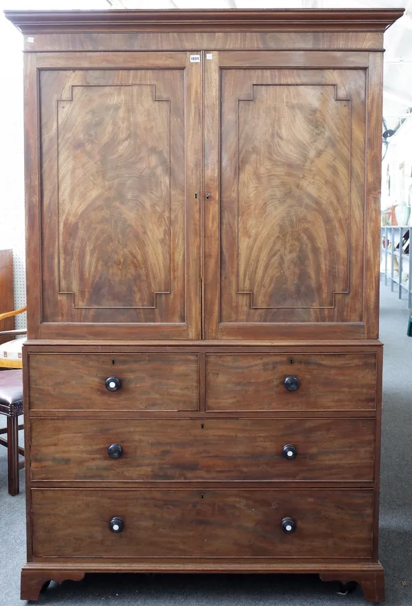 A George III mahogany linen press with a pair of panel doors over two short and two long graduated drawers on bracket feet, 129cm wide x 200cm high.