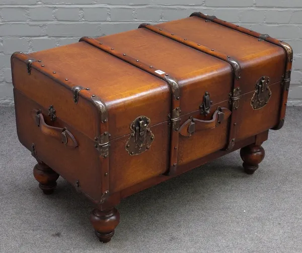 A coffee table formed as a wood and leather bound travelling trunk, on turned feet, 90cm wide x 56cm high.