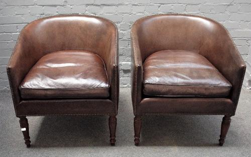 A pair of Regency style leather upholstered tub back armchairs, on turned supports, 66cm wide x 70cm high.