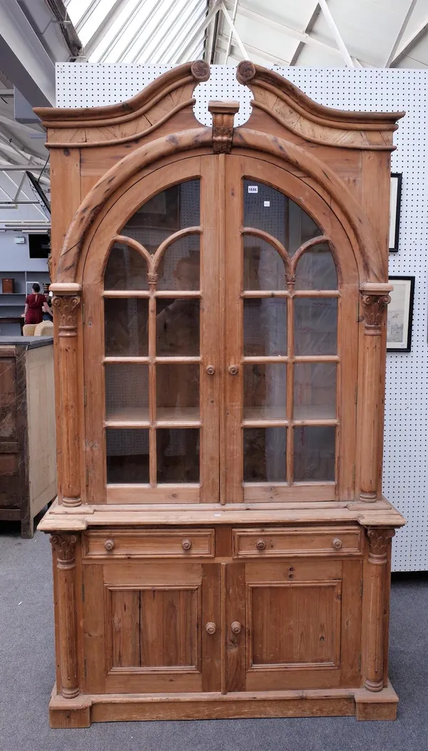 A pine display cabinet cupboard, the swan neck cornice over a pair of glazed doors and cupboards 122cm wide x 225cm high.