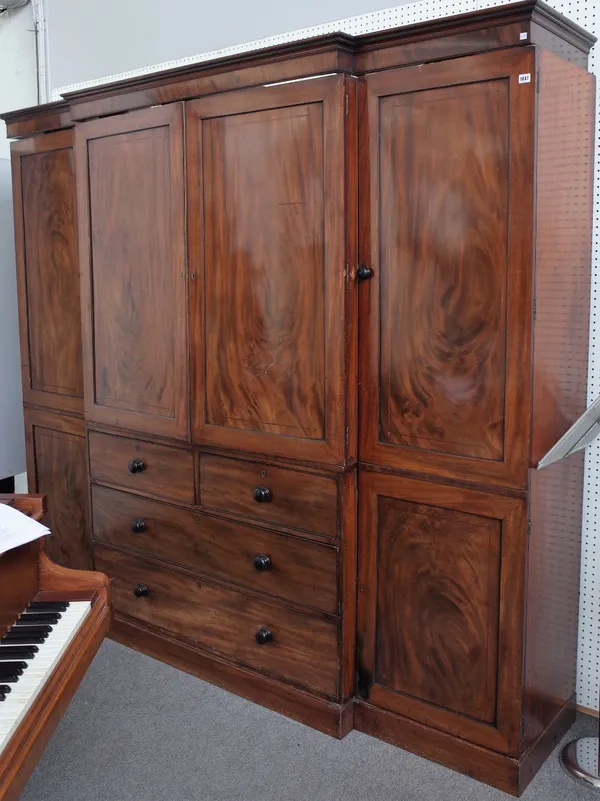 A George III mahogany breakfront compactum wardrobe with central cupboards over two short and two long graduated drawers, flanked by hanging cupboards