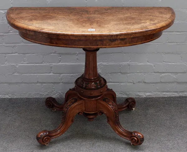 A Victorian inlaid figured walnut semi-elliptic card table, on four carved supports, 99cm wide x 74cm high.