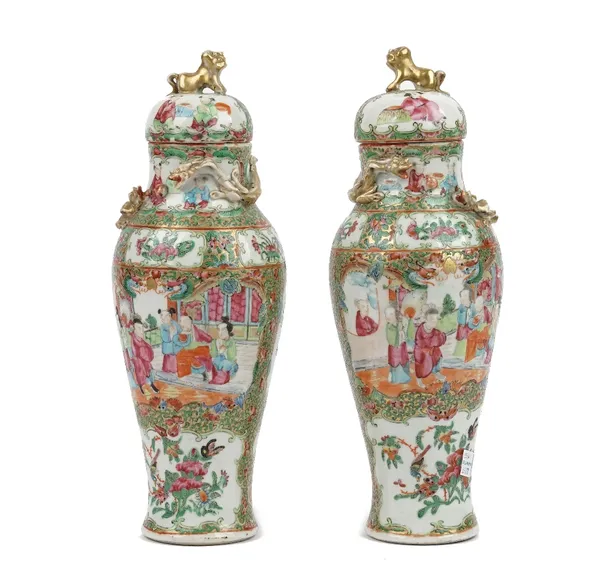 A pair of Canton famille-rose slender baluster vases and covers, 19th century, painted with panels of figures on terraces and birds amongst fruit and