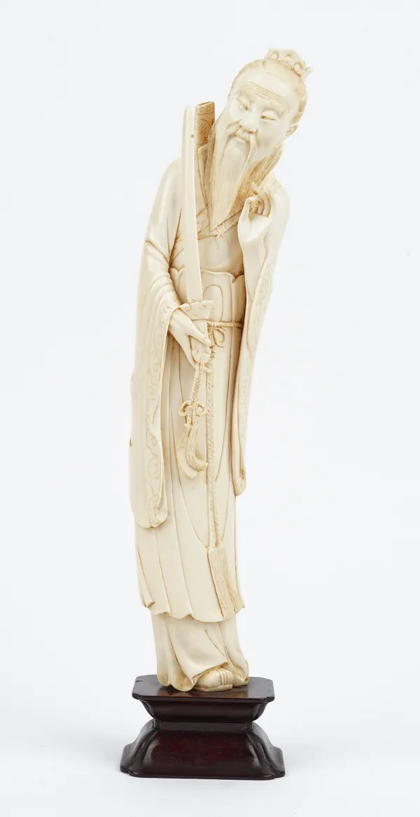 A Chinese ivory figure of a dignitary, early 20th century, carved standing in long robes carrying a ceremonial sword in his right hand, 30.5cm high, w