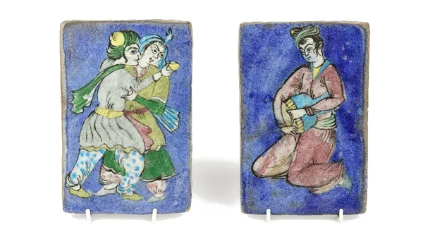 Two Qajar pottery rectangular plaques, late 19th/20th century, one moulded and painted with a figure with a drum, the other with a man and woman embra