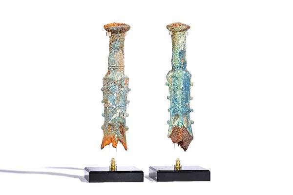 Two similar Chinese bronze sword hilts, Warring States period, fragments of an iron blade, each approx. 20.5cm high, modern stands.