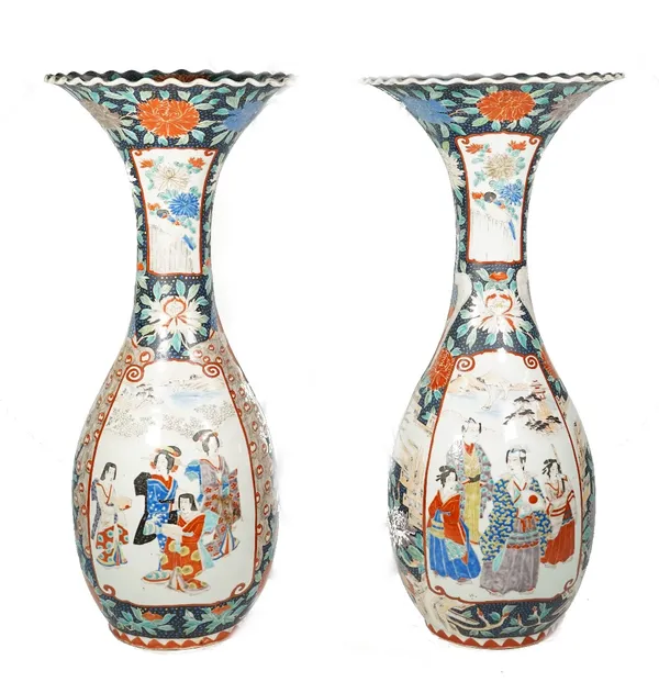 A pair of tall Japanese Imari slender baluster vases, Meiji period, each painted with figurative and bird panels against a dark blue ground enamelled