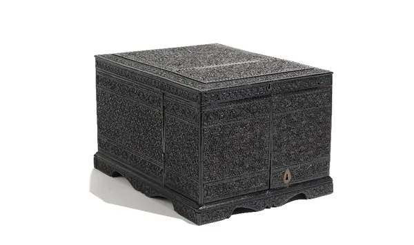 An Anglo Indian ebony dressing box, 19th century, overall carved with intricate foliate designs, the hinged cover inset with a dressing mirror inlaid