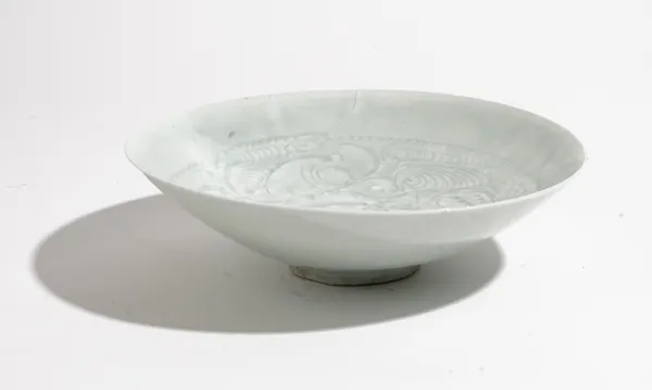 A Chinese qingbai shallow bowl, Song dynasty, incised with foliate scrolls beneath a light blue glaze, 20cm diameter.