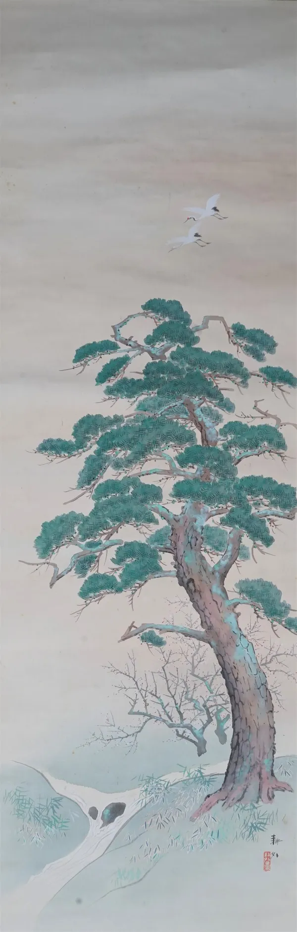 A Japanese scroll painting, painted with two cranes in flight above a pine tree, signed, 127cm. by 41.5cm.