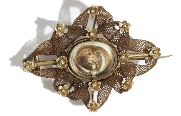 A gold and woven hairwork mourning brooch, first quarter of the 19th century, the centre with a glazed oval woven hairlocket, the interwoven hairwork