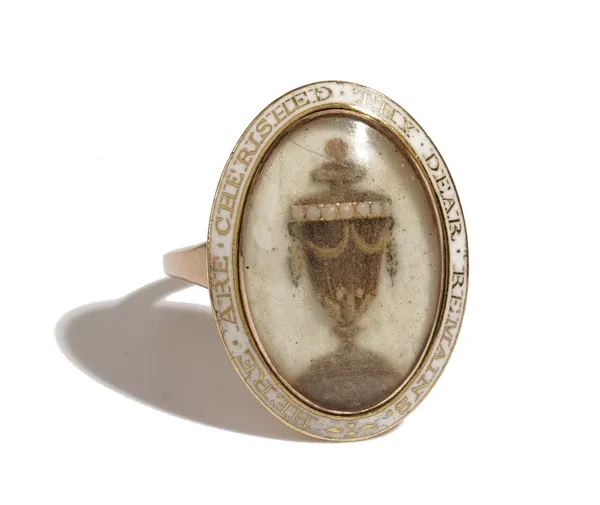 A gold and white enamelled mourning ring, circa 1800, the centre glazed with a hairwork urn, the enamelled border detailed 'Here are cherished thy dea