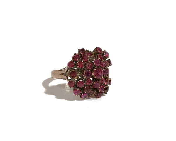 A gold and ruby cluster ring, claw set with circular cut rubies, in a raised design and with the principal ruby mounted to the centre, detailed indist