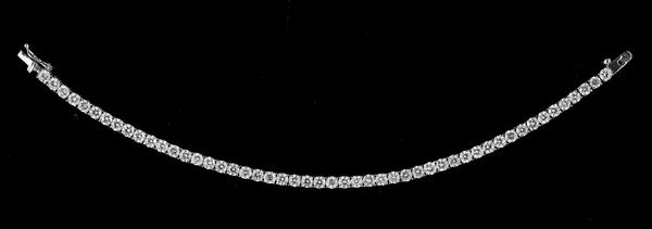 An 18ct white gold and diamond line bracelet, claw set with a row of fifty circular cut diamonds, on a snap clasp, with a foldover safety catch, lengt