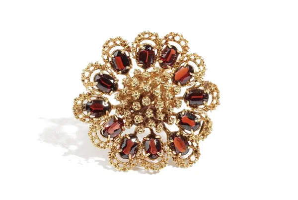 An 18 ct gold and garnet brooch, in a shaped circular abstract flowerhead shaped design, claw set with oval cut garnets, possibly London 1957, gross w