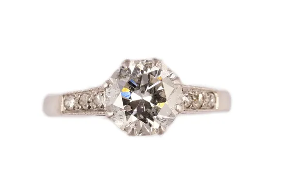 A platinum and diamond ring, claw set with the principal circular cut diamond to the centre, between diamond set three stone shoulders, unmarked, ring