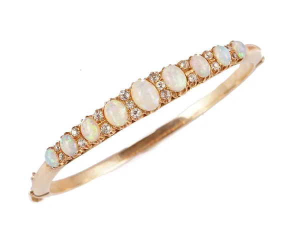 A gold, opal and diamond set oval hinged bangle, mounted with a row of nine graduated oval opals, with diamond set divisions at intervals, on a snap c