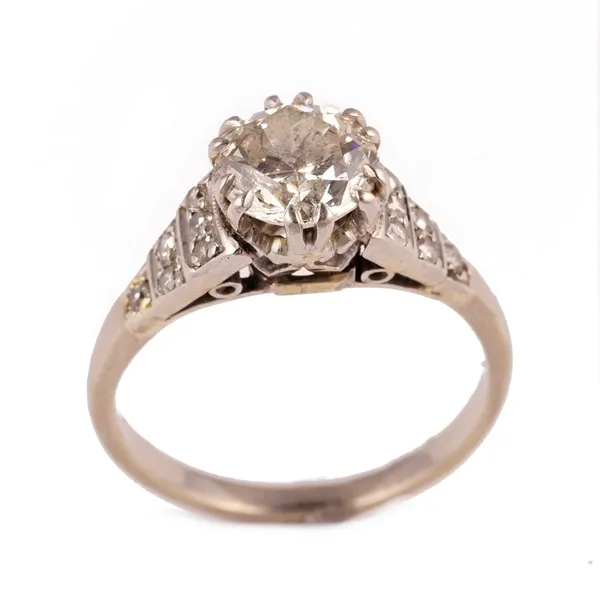 A diamond ring, claw set with the principal circular cut diamond between diamond six stone tapered shoulders, mounted with small cushion shaped diamon