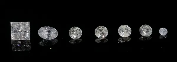 A group of seven unmounted loose diamonds, comprising; five circular cut, one oval cut and one princess cut, contained in three square boxes.