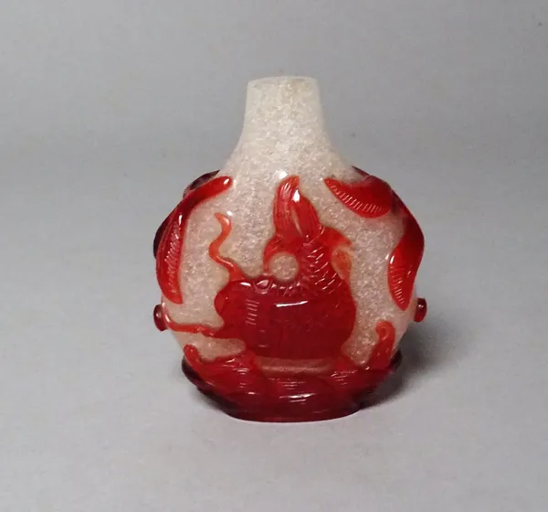 A Chinese red overlay glass snuff bottle, 19th century, each side carved with a mythical creature flanked by leafy branches, (a.f.), 5.5cm high.