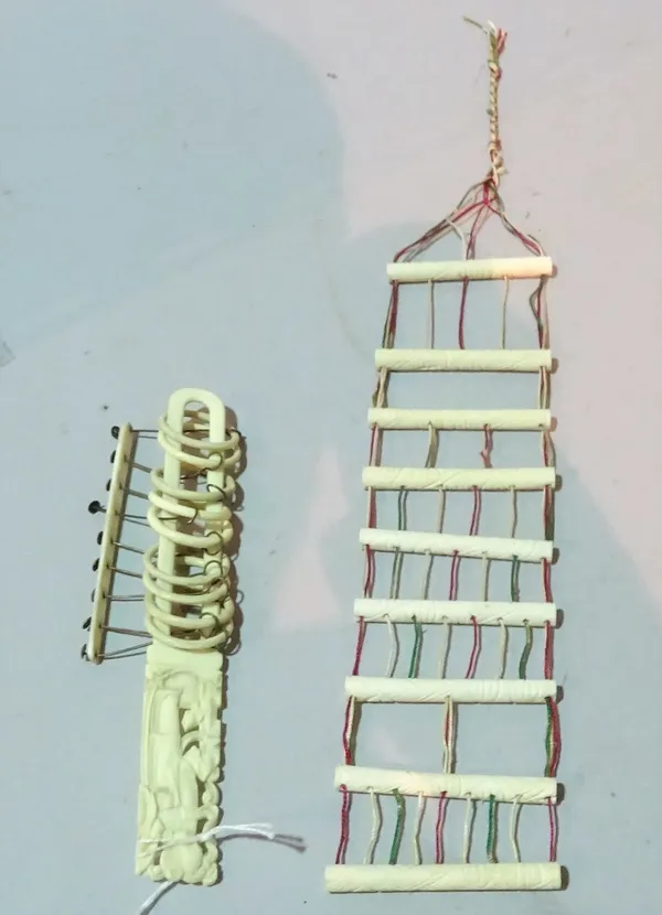 A Chinese ivory ring puzzle, 19th century, consisting of a long loop attached with nine rings, the top of the handle carved with a standing woman, 20.