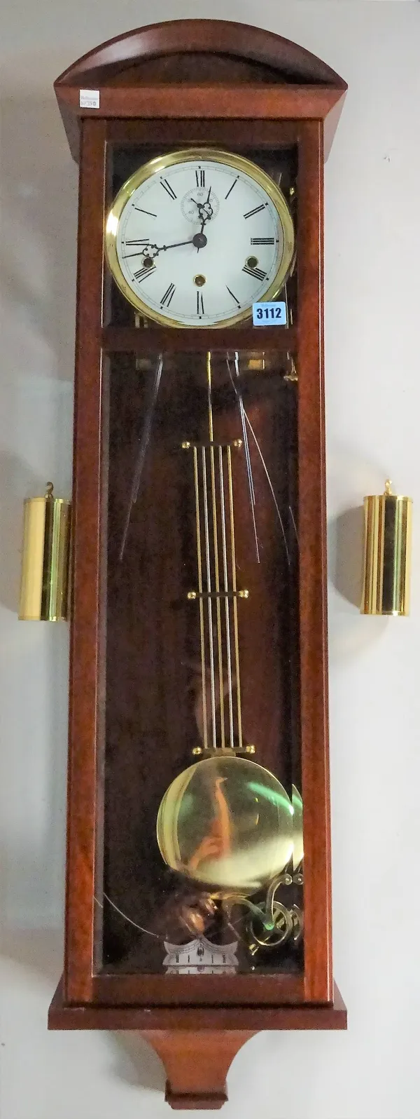 A modern mahogany Vienna style wall clock with mahogany case, bevelled glass panels and a chiming movement, 105cm high x 29cm wide.